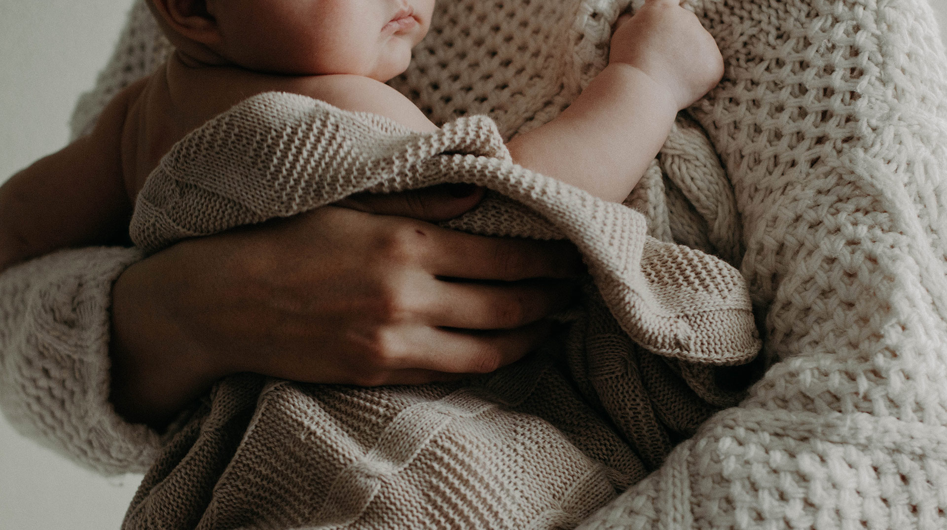 Close up of woman holding an infant wrapped in a blanket