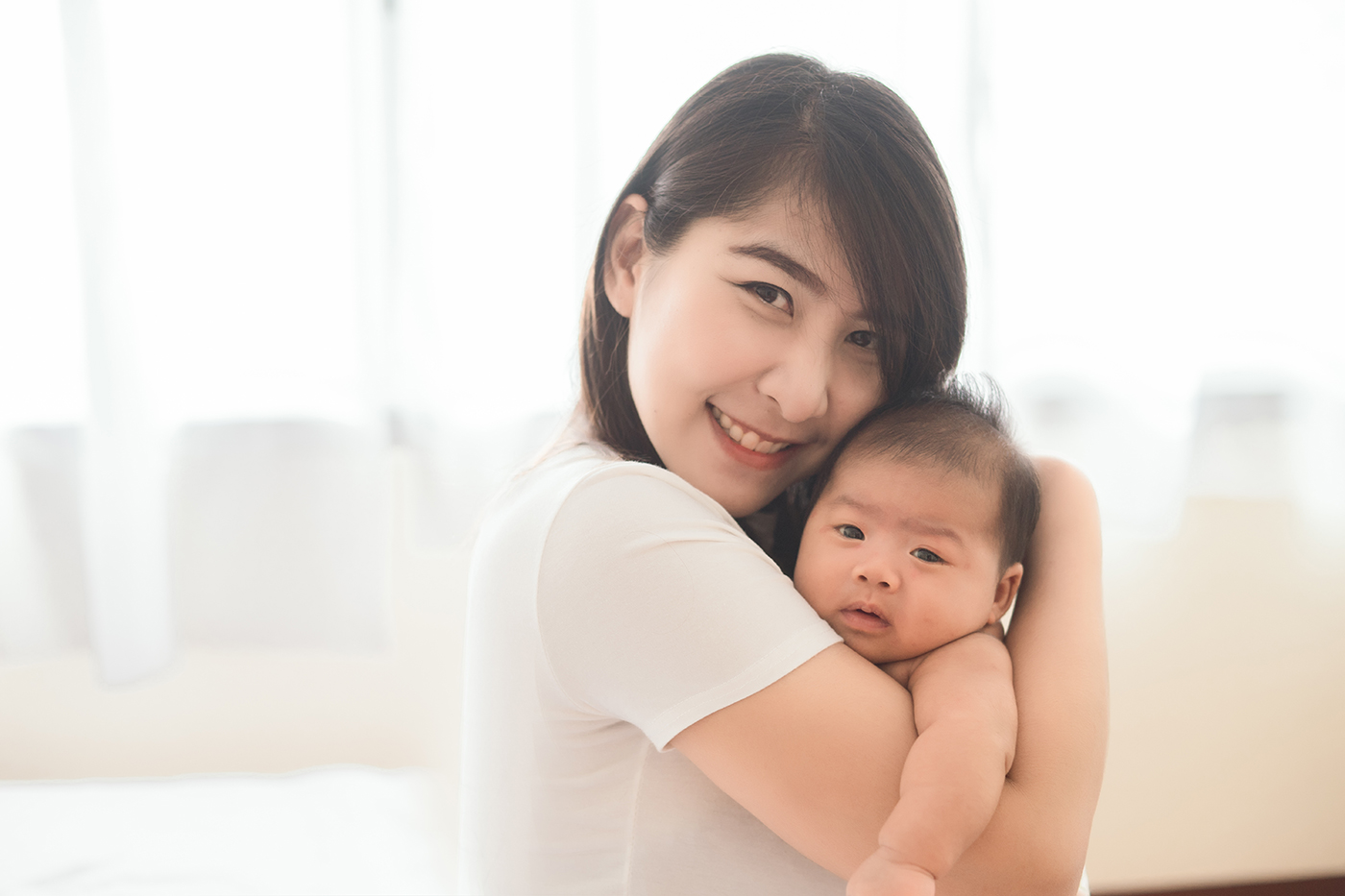 Mother holding baby close and smiling at camera