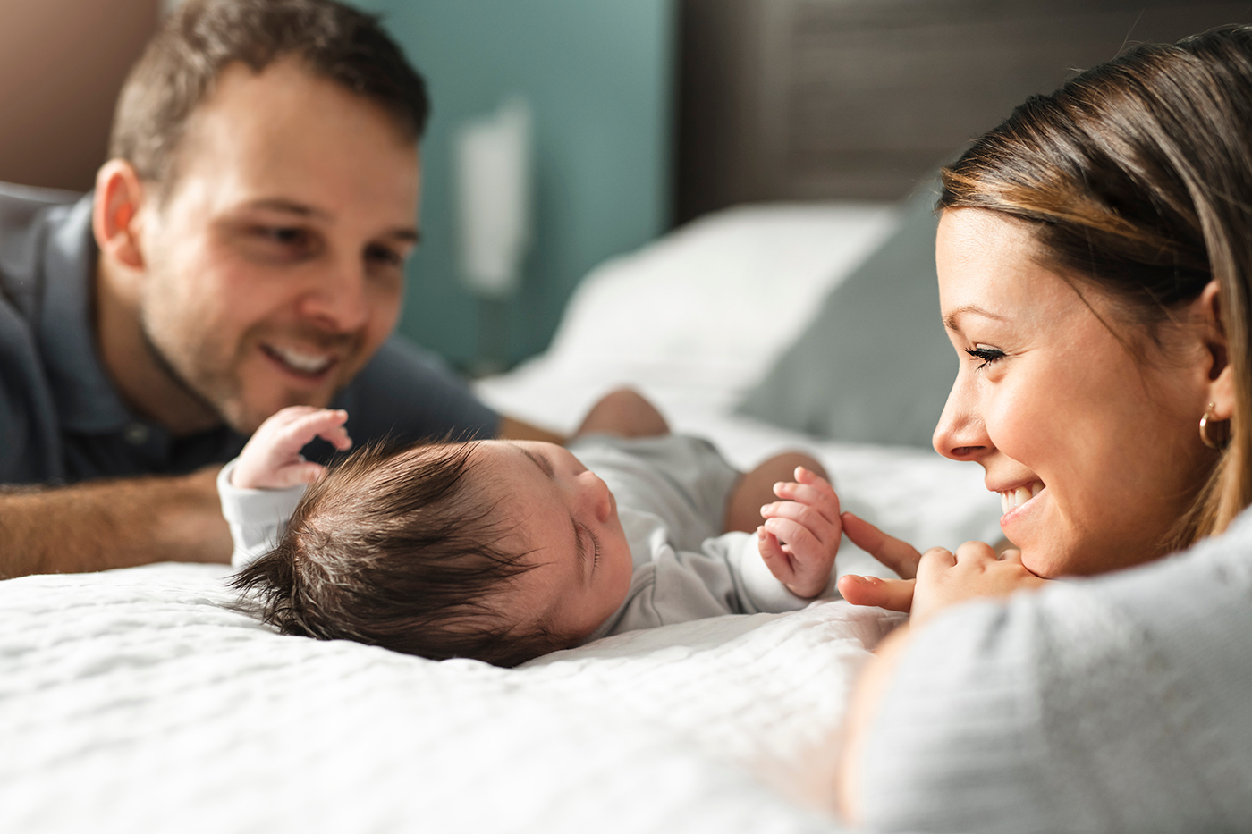 Parents gazing at infant on bed