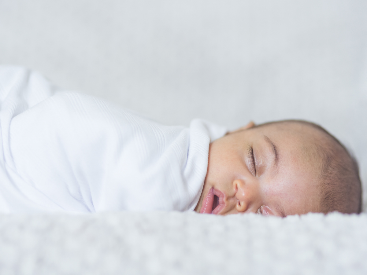 sleeping infant in white swaddle