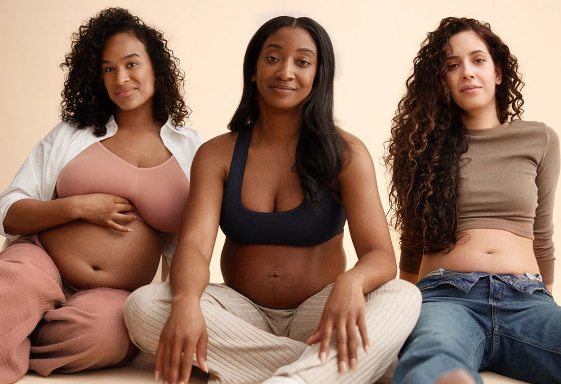 Three women sitting together. One woman is pregnant. Postpartum care